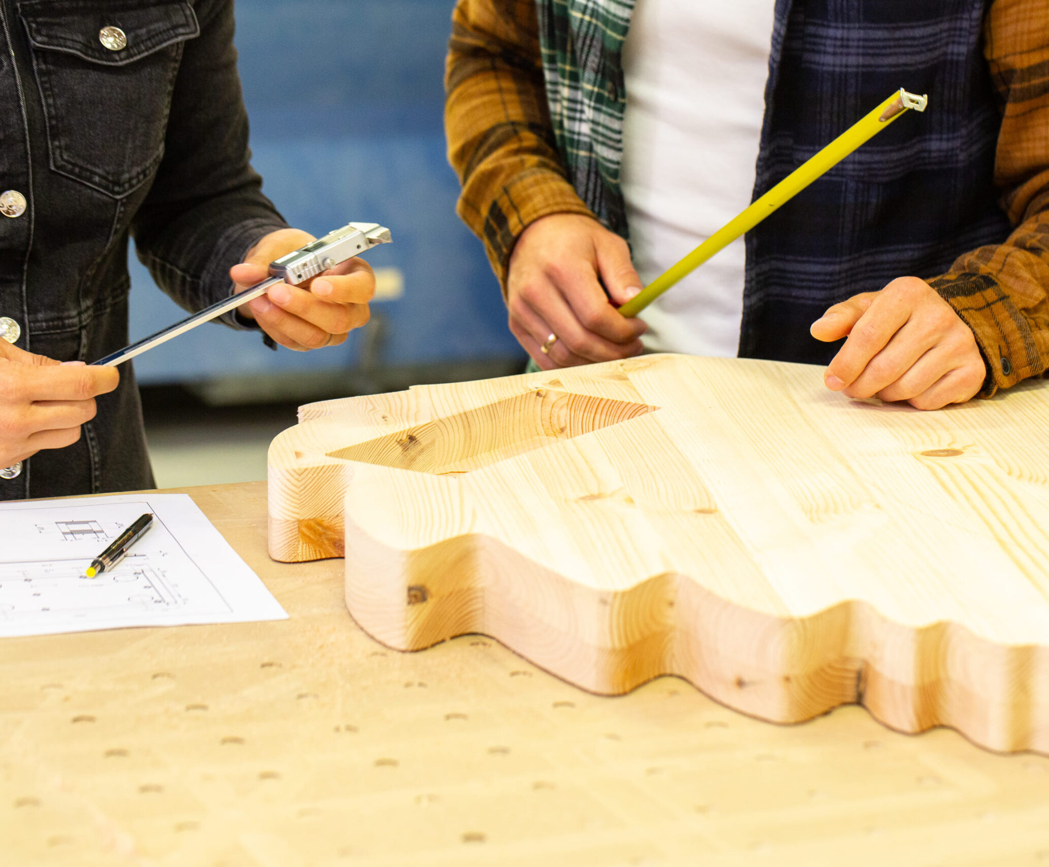 a person holding a pencil and a piece of wood